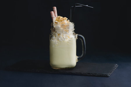 Cold vanilla milkshake in a vintage glass mason jar. Dark background with copy space for a menu.の写真素材