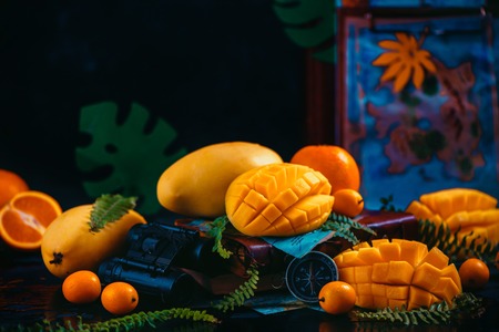 Mango, oranges, kumquat and other tropical fruits on a dark background with copy space. Traveling for the discovery of exotic fruits concept.の写真素材