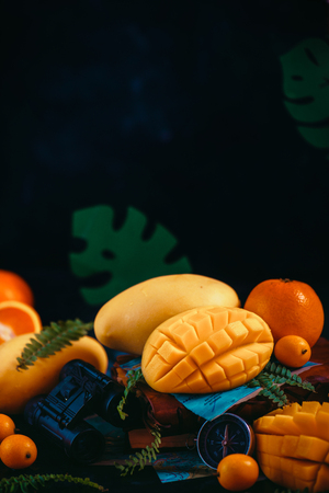 Mango close-up with oranges, kumquat, and other tropical fruits. Dark background with copy space. Traveling and discovery of exotic fruits concept.の写真素材