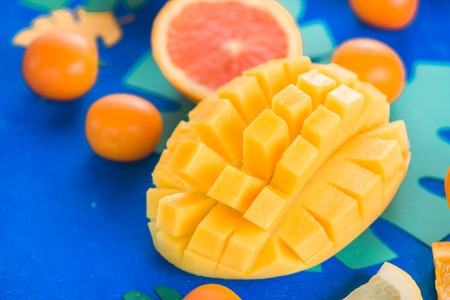 Exotic fruits close-up. Mango, oranges, kumquat and other tropical fruits vibrant blue background with copy space.の写真素材