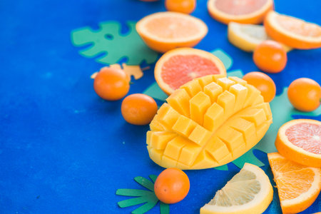 Exotic fruits close-up. Mango, oranges, kumquat and other tropical fruits vibrant blue background with copy space.の写真素材