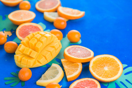 Exotic fruits close-up. Mango, oranges, kumquat and other tropical fruits vibrant blue background with copy space.の写真素材