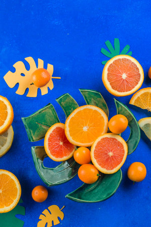 Exotic fruits close-up. Mango, oranges, kumquat and other tropical fruits vibrant blue background with copy space.の写真素材