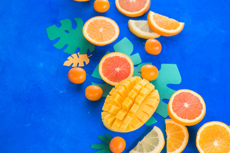 Exotic fruits close-up. Mango, oranges, kumquat and other tropical fruits vibrant blue background with copy space.の写真素材