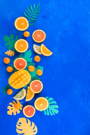 Citrus fruits, mango, oranges, kumquat, and other tropical fruits vibrant blue background with copy space. Exotic fruits close-up.の写真素材