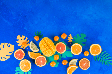 Tropic fruits on a vibrant blue background with copy space. Mango, oranges, kumquat, and other exotic fruits.の写真素材