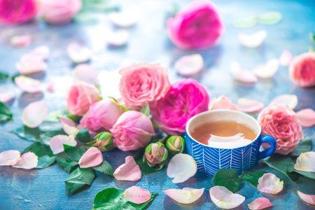 Rose tea photography with ceramic teacups and flower petals on a wet light background with copy space. Seasonal header with drinkの写真素材