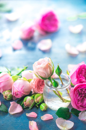 Pink roses in tiny glass bottles on a neutral gray background with copy space. A feminine concept with petals and flowers in pastel tonesの写真素材