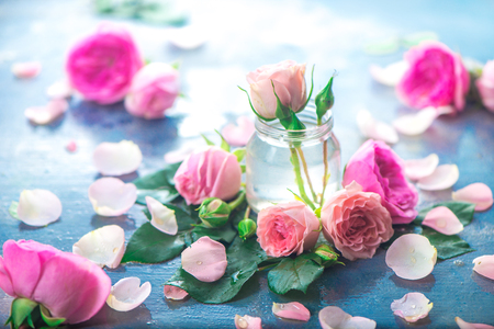 Glass bottles with pink peony roses on a light background with copy space. Feminine header with petals and flowers in pastel tonesの写真素材
