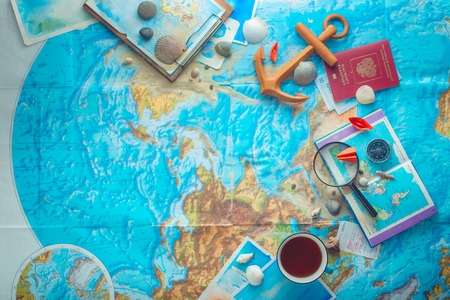 Adventure and traveling flat lay with a map, wooden anchor, paper airplanes, passport and a magnifying glass. Flat lay with copy spaceの写真素材