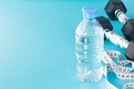Empty space for the text. Slimming. A measure tape, dumbbells, a bottle of water on a sports mat.の写真素材