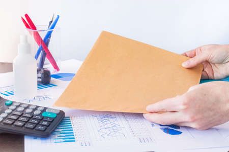 Empty space for text. Workplace in the office. Blank brown envelope in a hands.の写真素材