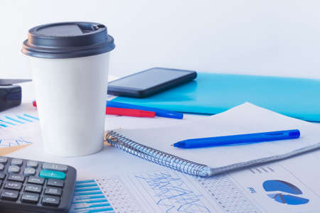 Empty space for the text. Coffee to go in a white paper cup with a blank place for logo. Workplace in the office.の写真素材
