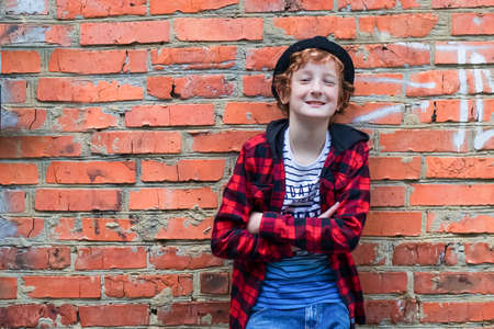 Empty space for the text. A boy 11-13 stands against a red brick wall and smiles. Soft focus.の写真素材