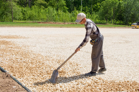 A worker on a construction site levels rubble with a shovel