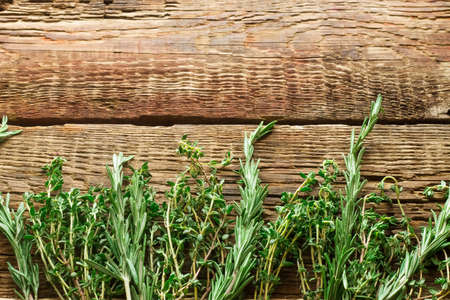 Empty space for text. Green thyme and rosemary on a brown woody background.の写真素材