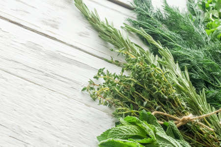Empty space for text. Bunches of rosemary, mint, thyme, dill on a white wooden tableの写真素材