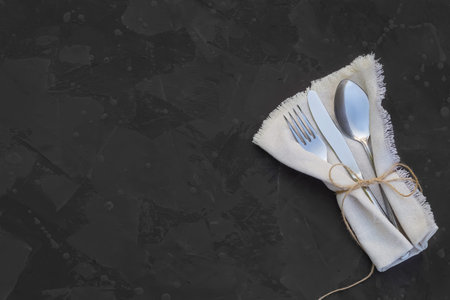 Empty space for text, recipe, menu, ad. Fork, knife, spoon, napkin on a dark background.