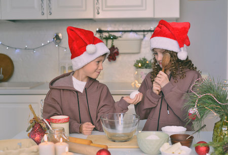 Children are cooking christmas cookies. The are in the kitchen at home.