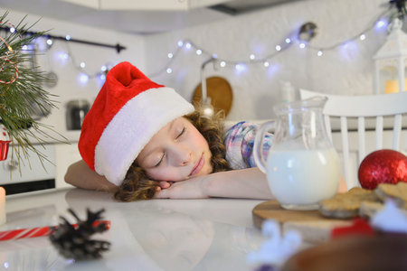 A little girl is sleeping and waiting for Santa. She prepared milk and cookies for santa. horizontal...