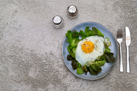 Fried egg with green salad on the plate. Concrete background. top view. Copy space. Healthy diet.