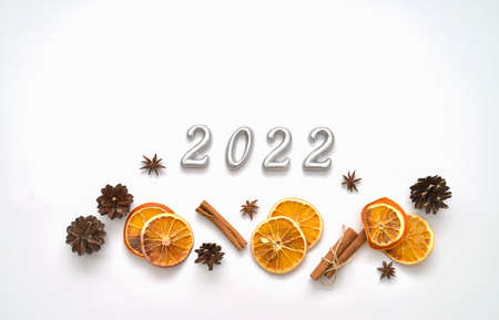 New year decoration. Writing of 2022 on the white background.orange slices, cinnamon and cones.の写真素材