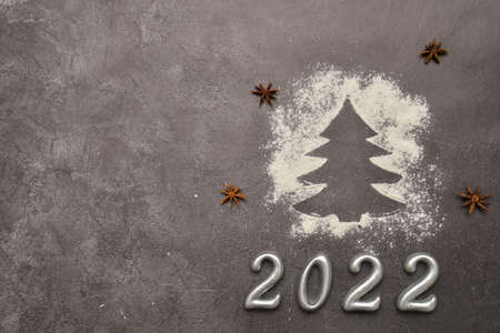 silhouette of a Christmas tree made of flour on the black background. Writing of 2022.の写真素材
