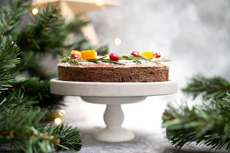 Christmas cake is on the cake stand with candles, tree branches and craft star on the wall. Dark grye background. Horizontal frame.の写真素材