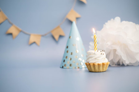 cake with yellow candle with birthday cap in a blue backgroundの写真素材