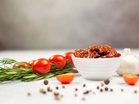 Sun dried tomatoes with fresh herbs, spices, tomatoes and garlik. Grey background.の写真素材