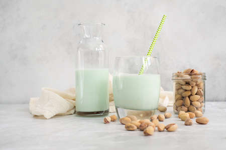 pistachio milk in a glass and in a bottle with straw and pistachios on a grey background. Horizontal frame.の写真素材