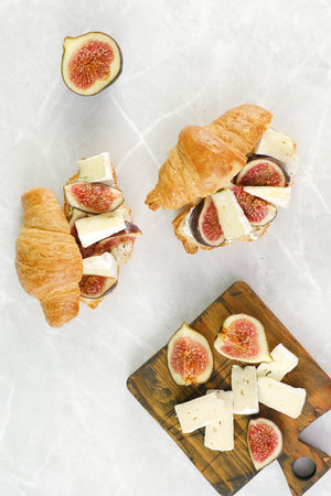Croissant burger with figs, cheese and honey on a marble background. Top view.の写真素材