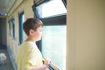 The little boy is looking throw the window in a train. Summer time.Travelling by a train.の写真素材