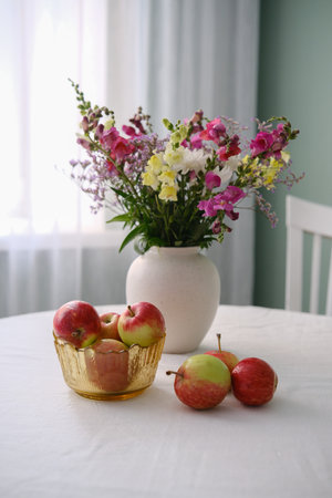 A Beautiful Display of Fresh Apples and Vibrant Flowers Set Elegantly on a Table Surfaceの写真素材