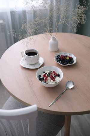 A Cozy Breakfast Setting Featuring Coffee and Berries Beautifully Arranged on a Wooden Tableの写真素材