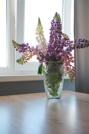 A Vibrant and Beautiful Floral Arrangement in a Glass Vase Sitting on a Wooden Tableの写真素材