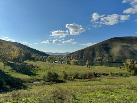 A Serene and Beautiful Landscape Featuring Rolling Hills and a River Beneath a Clear Blue Sky