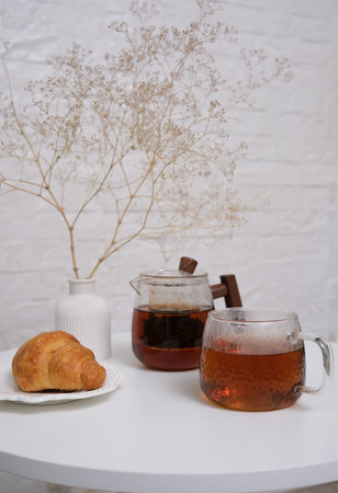 Enjoy a delightful tea time with a croissant and beautifully arranged dried flowersの写真素材