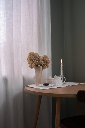 A Cozy Tea Setup Featuring a Beautiful Candle and Delicate Dried Flowers for Ambianceの写真素材