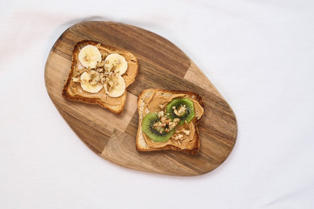A Delicious and Healthy Toast Topped with Slices of Banana and Kiwi on a Wooden Board on white background.の写真素材