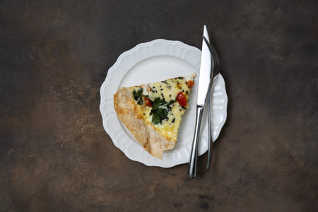 A delicious and savory slice of vegetable quiche is beautifully served on a classic white plate with...