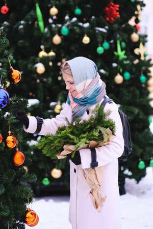 A woman joyfully touching atoy on a Christmas tree with colorful ornaments, spreading holiday cheer to those around herの写真素材