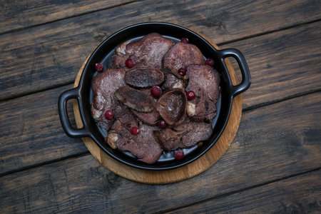 A Plate of Delicious , tasty roasted beef tongue accompanied by berries on black plate.の写真素材
