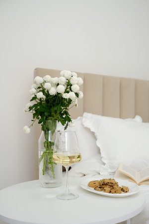 An Elegant Bedroom Setup Featuring Beautiful Flowers, a Candle, and a Glass of Wine