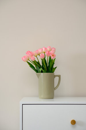 A beautiful arrangement of pink tulips displayed in a ceramic vase placed on a white table.の写真素材