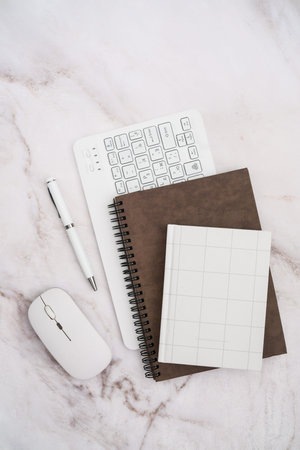 A stylish flat lay of a modern workspace featuring stationery - notebooks, pen, and sleek tech...