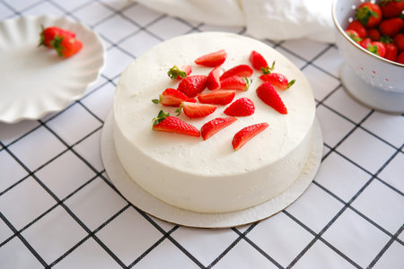 A Scrumptious and Delicious Strawberry Topped Cake Gracing a Classic Checkered Tablecloth