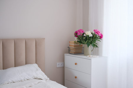 An Elegant Bedroom Corner Bathed in Soft Lighting Surrounded by Fresh Flowers and Beautyの写真素材