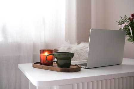 Homeoffice with Christmas decoration - Notebook, green glass with coffee, candle on white table.の写真素材