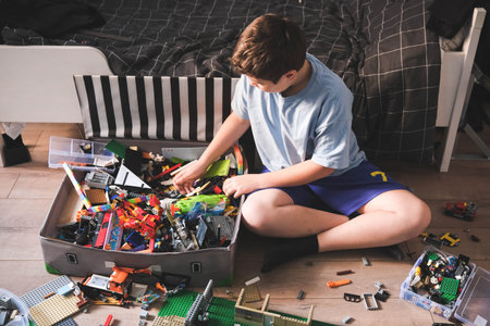 Child boy playing and building with colorful plastic bricks on the floor in the room. Learning and development.の写真素材